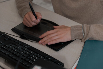 Close-up of the artist's hands of a designer drawing with a stylus on a tablet