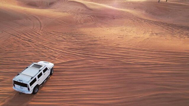 Car driving through sand dunes in the desert