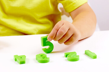 The child shows the number 5. Early development, playing with numbers, learning to count. selective focus