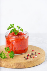 Paste ajvar from sweet pepper and spices in a jar on a light background. Preservation for the...