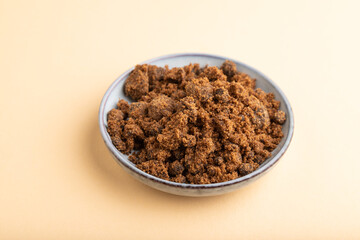 plate with unrefined cane sugar on orange pastel. side view, close up.