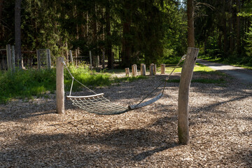 Hängematte - Liegeschaukel aus Holz und Seilen auf einem Spielplatz im Wald