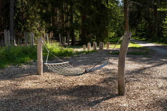 H&auml;ngematte - Liegeschaukel aus Holz und Seilen auf einem Spielplatz im Wald