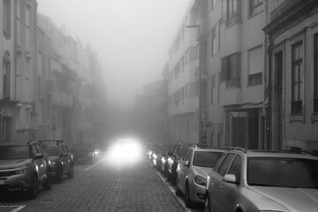 View of a street in the morning in dense fog. Porto, Portugal. Black and white photo.