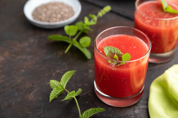 Watermelon juice with chia seeds and mint in glass on a black concrete background with green textile. Side view,  selective focus.