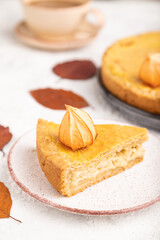 Autumn onion pie decorated with leaves and cup of coffee on gray concrete background. Side view, selective focus.