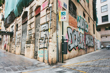 A grungy street corner with graffiti  painted on the decaying wall