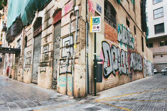 A grungy street corner with graffiti  painted on the decaying wall