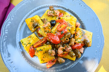 Pasta with tuna steak, olives and cherry tomatoes. Lunch served on table in restaurant. Italian cuisine. 