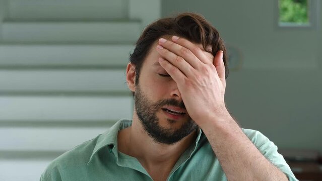 Charming young bearded dark-haired Caucasian man feels shocked by what he saw, he covers his face and expressing denial and dissatisfaction. Embarrassment, confusion, dissatisfaction, disagreement