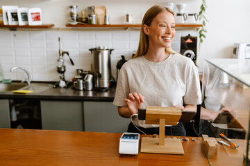 Blonde white barista woman working with tablet computer in cafe