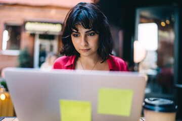 Serious woman working on computer in cafe