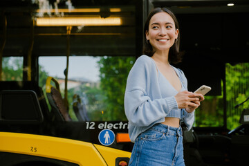 Young beautiful smiling happy asian girl with phone looking aside