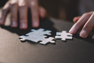 Close-up of business hands connecting jigsaw puzzle, success and goal achievement, the last jigsaw...