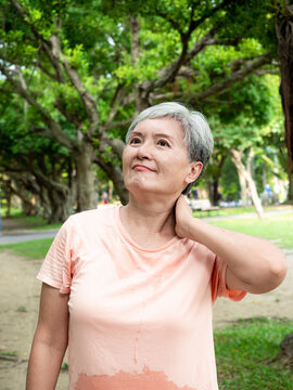 Portrait of mature asian woman 60s with shoulder pain at park outdoor.