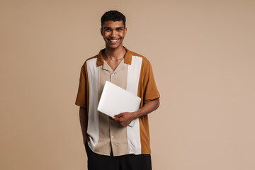 Young handsome smiling african man holding laptop looking at camera