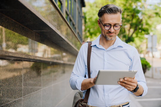 European grey man using tablet computer while standing at city street