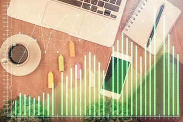 Double exposure of financial chart hologram over desktop with phone. Top view. Mobile trade platform concept.