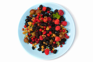 On a white background a plate with summer berries. Fruit salad with raspberries, gooseberries, currants, mulberries. Flat lay, top view