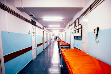 Long hospital corridor with gurneys without people.