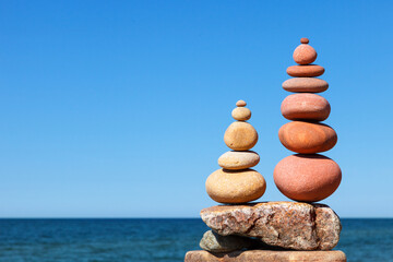 Two Rock zen pyramids of colorful pebbles on a beach on the background of the sea.