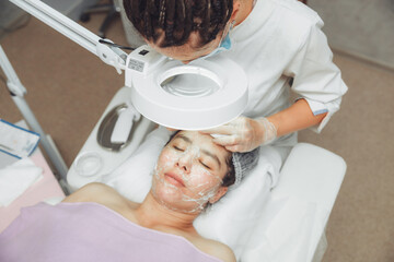 Cosmetic facial cleansing procedure for a young woman using a spoon uno. acne treatment. mechanical...