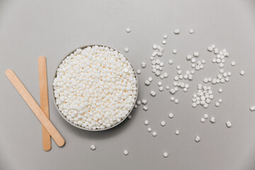 Cosmetic depilation kit. white wax granules for hair removal in a metal jar and wooden strips....