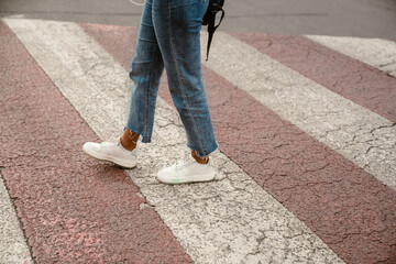 Young black woman wearing jeans walking on pedestrian crossing