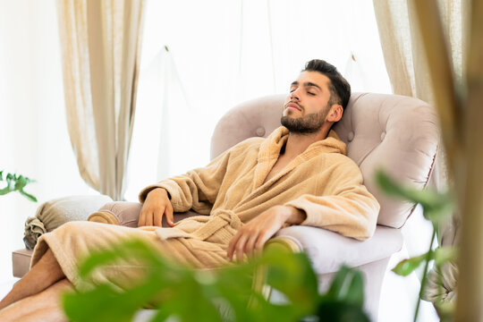 Young man relaxing in armchair in spa salon