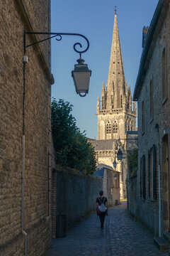 A view from a small street with woman to the Notre-Dame church in the centre of Carentan, Manche, Normandy, France