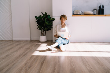 Focused woman sitting with laptop on floor