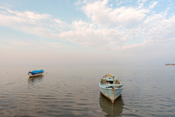 Fototapeta na wymiar Fishers boats on the lake, calm water with beautiful reflection of colorful sky tranquily scene