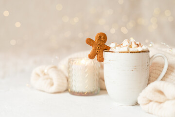 Gingerbread man cookie in cup of hot cocoa or coffee with marshmallow, candle, cinnamon and warm...