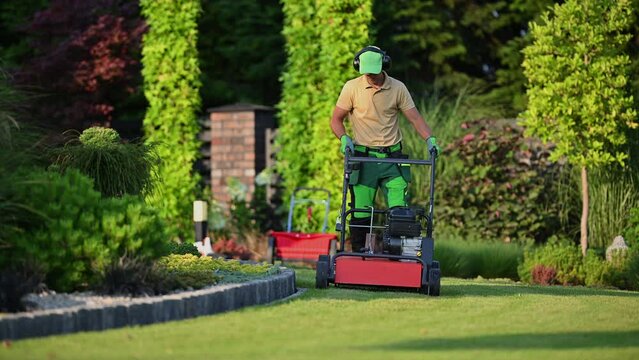 Backyard Garden Work with Lawn Aerator. Machine and Working Caucasian Gardener. Gardening Equipment.