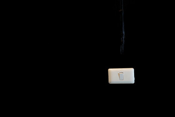 A white switch is used to turn the lamp on and off on a black wall.