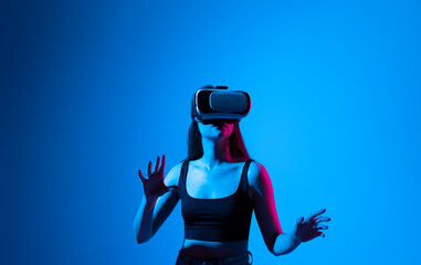 Metaverse technology concept. Confident brunette young woman in virtual reality headset pointing in...