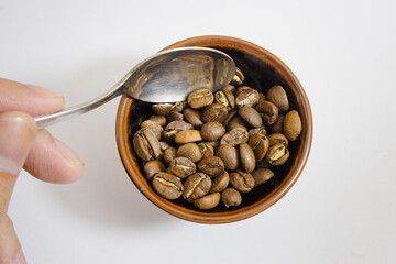coffee beans isolated in a bowl with spoon and hand,white background