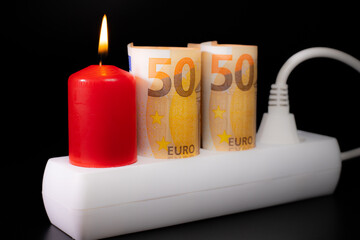 Obraz premium Energy price increase. Burning candles in an electrical extension cord. Increase in energy bill prices.