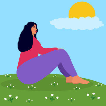 Young woman sits on a flower meadow.
