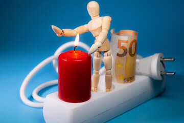 Energy price increase. Burning candles with a wooden man warming himself by the candle. Increase in energy bill prices.