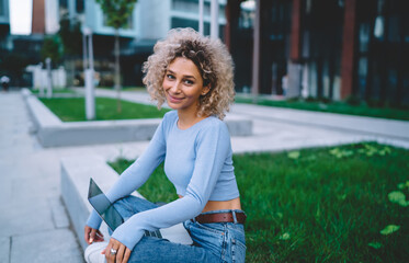 Smiling woman with netbook sitting near building