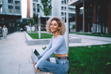 Smiling freelancer with netbook sitting on bench