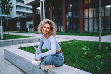 Smiling ethnic woman with laptop in city