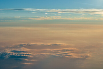 Naklejka na ściany i meble View over the clouds. Cloud cover seen from an airplane. Beautiful sunset sky above clouds. Beautiful orange and pink sunrise over the clouds