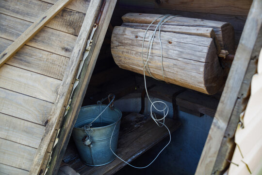 Wooden water well with a bucket. Close up.