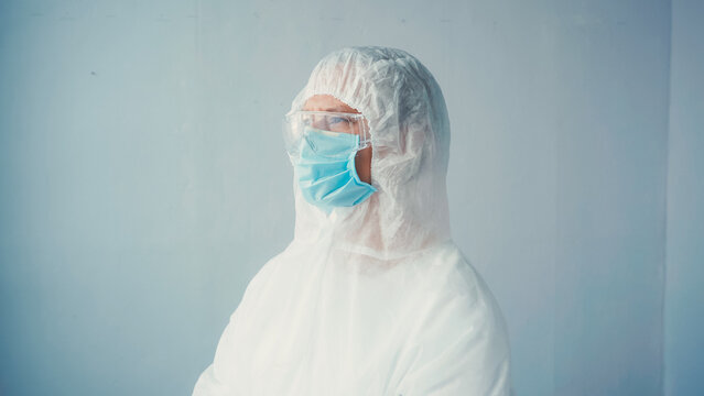 Doctor In Hazmat Suit And Goggles With Medical Mask On Grey Background.