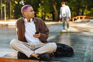 Young handsome stylish boy with headphones and phone looking aside