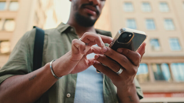 Young smiling man with beard dressed in an olive color shirt uses phone map app on the old city background - Powered by Adobe