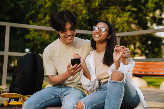 Young handsome smiling asian boy hugging beautiful happy african girl