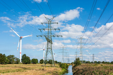 Windkraftanlagen und Hochspannungsmasten an der Nordseeküste im Sonnenschein
